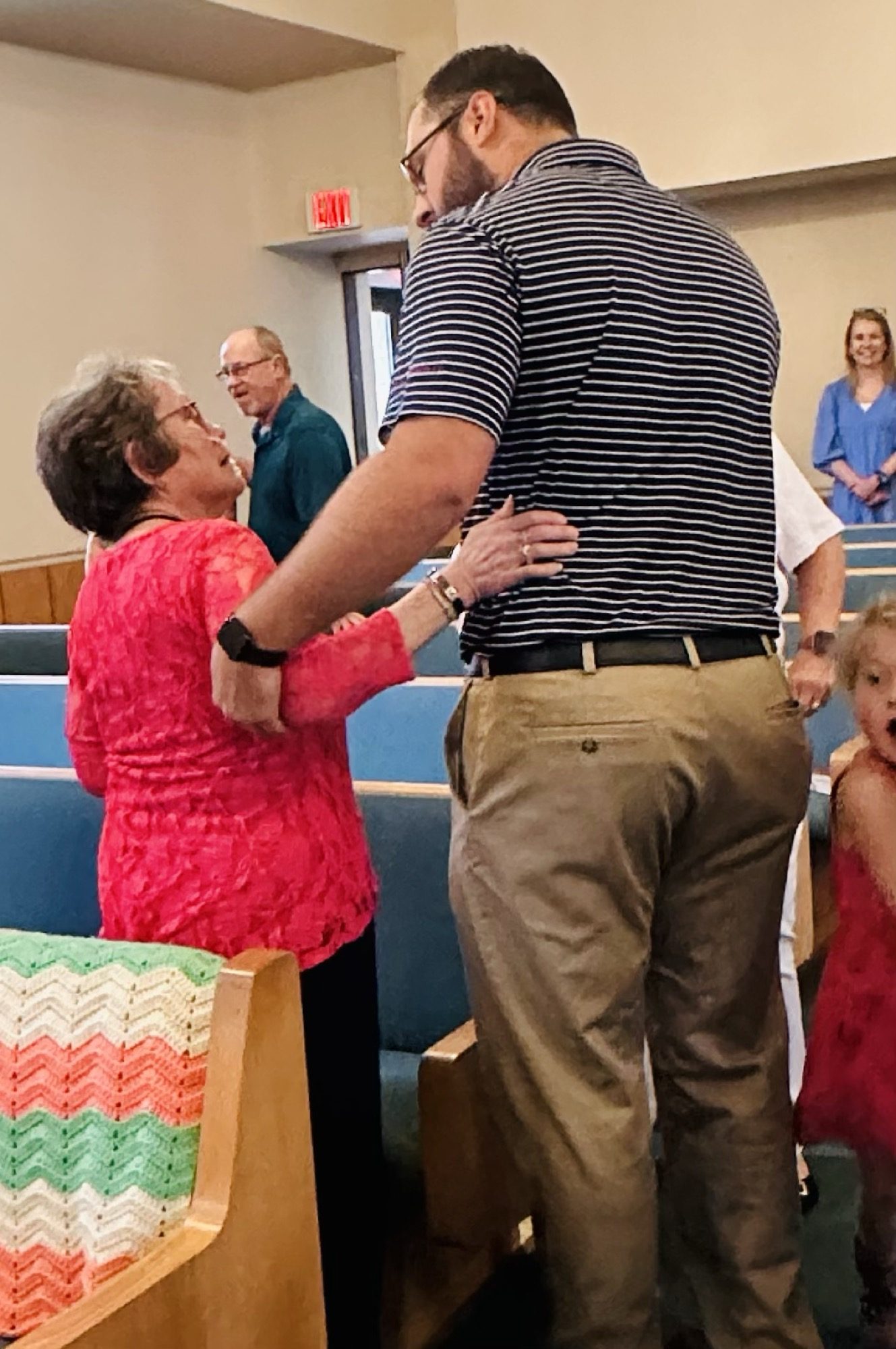 A member welcoming a couple before worship