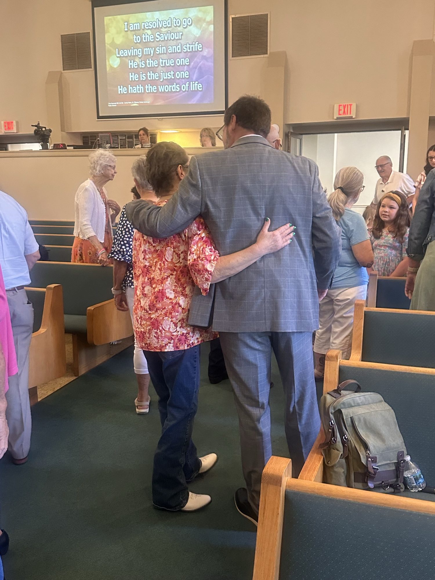 Two members sharing an embrace during Sunday worship